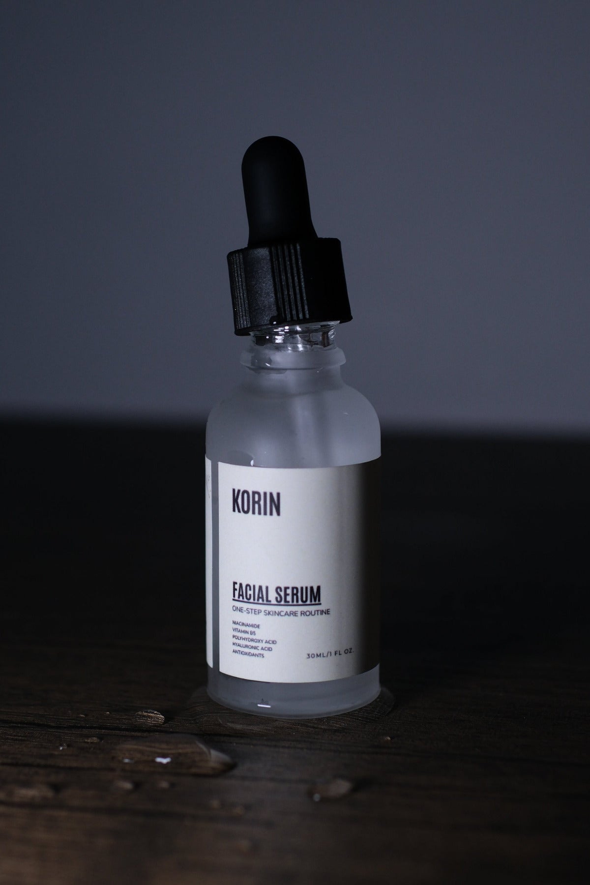 Bottle of facial serum with dropper on a wooden surface and dark background